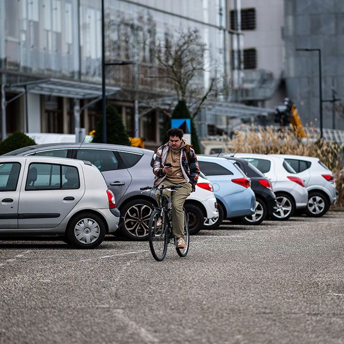 Un cycliste traverse un parking de l'université de Bordeaux